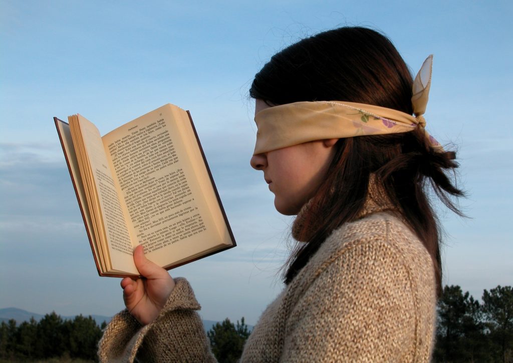 Student trying to read a in Spanish while blindfolded.